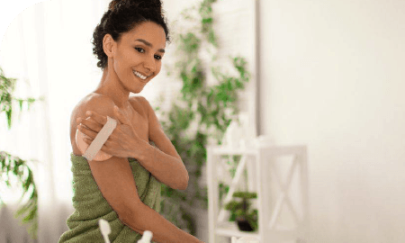 jeune femme se frottant l'épaule à l'aide d'une brosse/éponge