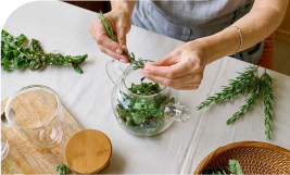 une personne en train de préparer une tisane avec des herbes fraiches
