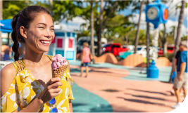 une femme souriante dans un square qui mange une glace