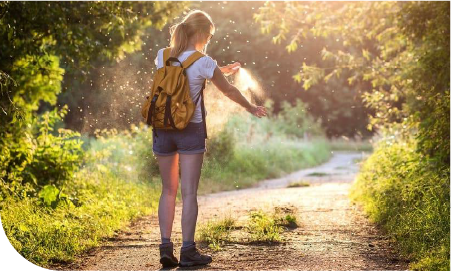 une femme sur un sentier se tapant le bras pour chasser un moustique