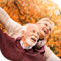 couple de personnes âgées souriants dans un paysage automnal