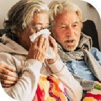 couple de personnes âgées avec des écharpes. La femme se mouche dans un mouchoir en papier.