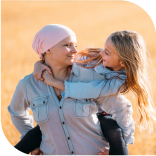 une maman qui a eu un cancer portant sa fille sur le dos