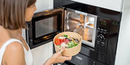 Femme qui met un plat dans un micro-ondes