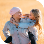 une maman qui a eu un cancer portant sa fille sur le dos