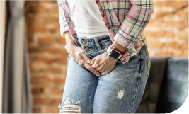 une femme en jean et pull qui s'appuie sur le pubis car elle a envie d'uriner et mal