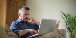 Personne assise dans son canapé devant un ordinateur portable et froncant les sourcils