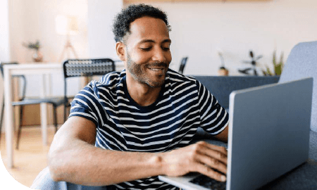 homme 30-40 dans son salon devant son ordinateur portable