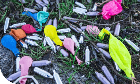 bombonnes de protoxyde d'azote et ballons jonchés sur le sol
