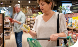 Femme regardant une conserve et poussant son caddie