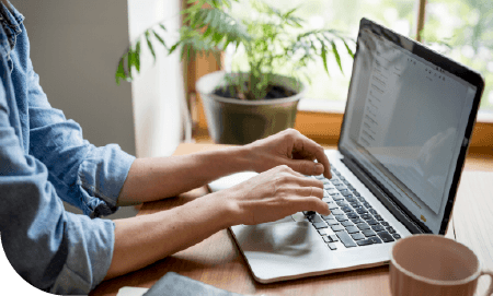 mains de femme tapant sur un clavier d'ordinateur portable dans ce qui semble être son salon