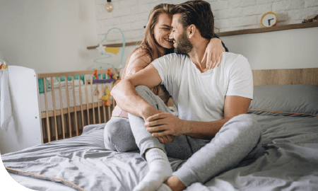 un couple habillés assis sur un lit et s'enlaçant