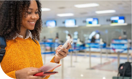 une femme souriante consulte son téléphone dans un aéroport
