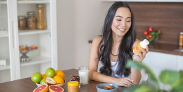 femme regardant un jus de fruits avec des fruits devant elle