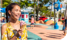 une femme souriante dans un square qui mange une glace