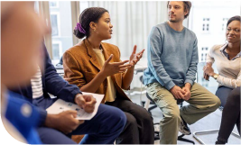 groupe assit en cercle dans une salle de réunion une femme prend la parole