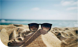 les lunettes de soleil posées sur du sable avec la mer en arrière plan