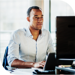 Un homme en chemise derrière son écran d'ordinateur