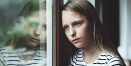 Jeune enfant triste regardant dans le vide à travers une fenêtre