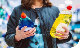 Une femme regardant des bouteilles de produit vaisselle
