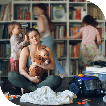 maman seule avec bébé dans les bras dans son salon avec des enfants qui jouent et s'agitent derrière elle