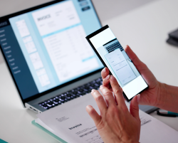 prise de photo d'un document avec un smartphone, ordinateur en arrière plan