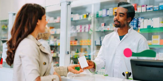 Pharmcien donnant une boite de médicaments à une cliente