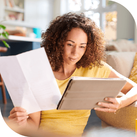 femme 30-40 en train de regarder des documents administratifs dans son salon