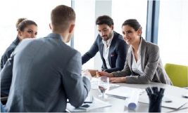 Des hommes et femmes en costume autour d'une table en réunion